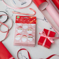 Load image into Gallery viewer, Pack of pink scented sachets with watercolor santas on it displayed on a marble background with gift wrapping supplies