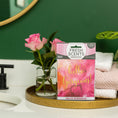 Load image into Gallery viewer, A bathroom counter with a gold tray displays a glass vase of pink roses, folded towels, and a Fresh Scents Hello Gorgeous - Sachet 3pk for long-lasting fragrance. In the background are a sink, green wall, and round mirror.