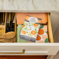 Load image into Gallery viewer, An open kitchen drawer holds neatly folded colorful dish towels, wooden utensils, tray-organized knives, and a Fresh Scents Orange & Honey - Sachet 3pk on top for a long-lasting fragrance.