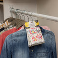 Load image into Gallery viewer, A closet rod holds several clothes, including a denim shirt in front. Hanging among them is a Fresh Scents Happy Chicken - Sachet 3pk, offering lasting fragrance without the need for flameless air fresheners.