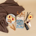 Load image into Gallery viewer, A pack of three scented sachets with a dragonfly design and the phrase 'Live in the Moment' on the packaging, displayed on a tan background with almonds, peaches, and other fragrance ingredients.