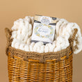Load image into Gallery viewer, A woven basket holds a chunky white knit blanket and a Fresh Scents Lets Stay Home - Sachet 3pk, a long-lasting flameless air freshener, set against a beige background.