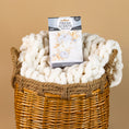 Load image into Gallery viewer, A woven basket holds a chunky white knit blanket and a Fresh Scents Fall & Family - Sachet 3pk, delivering long-lasting fragrance, set against a beige background.