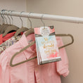Load image into Gallery viewer, Several shirts, including a pink striped button-down, hang in a closet. A Fresh Scents "She Believed - Sachet 3pk" provides flameless fragrance from one hanger, displaying the quote: "She believed she could so she did.