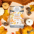 Load image into Gallery viewer, The Autumn Leaves - Sachet 3pk by Fresh Scents rests on a beige surface among autumn leaves, pumpkins, and acorns, filling the air with a cozy, long-lasting fall fragrance.