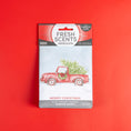 Load image into Gallery viewer, The Fresh Scents Merry Christmas - Sachet 3pk features a red truck with a Christmas tree on a red background, providing flameless fragrance and long-lasting holiday freshness.