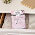 Load image into Gallery viewer, A Fresh Scents Faith Hope Love - Sachet 3pk is displayed in an open white dresser drawer lined with floral and striped fabric, providing long-lasting fragrance. A book and a vase are on top of the dresser.