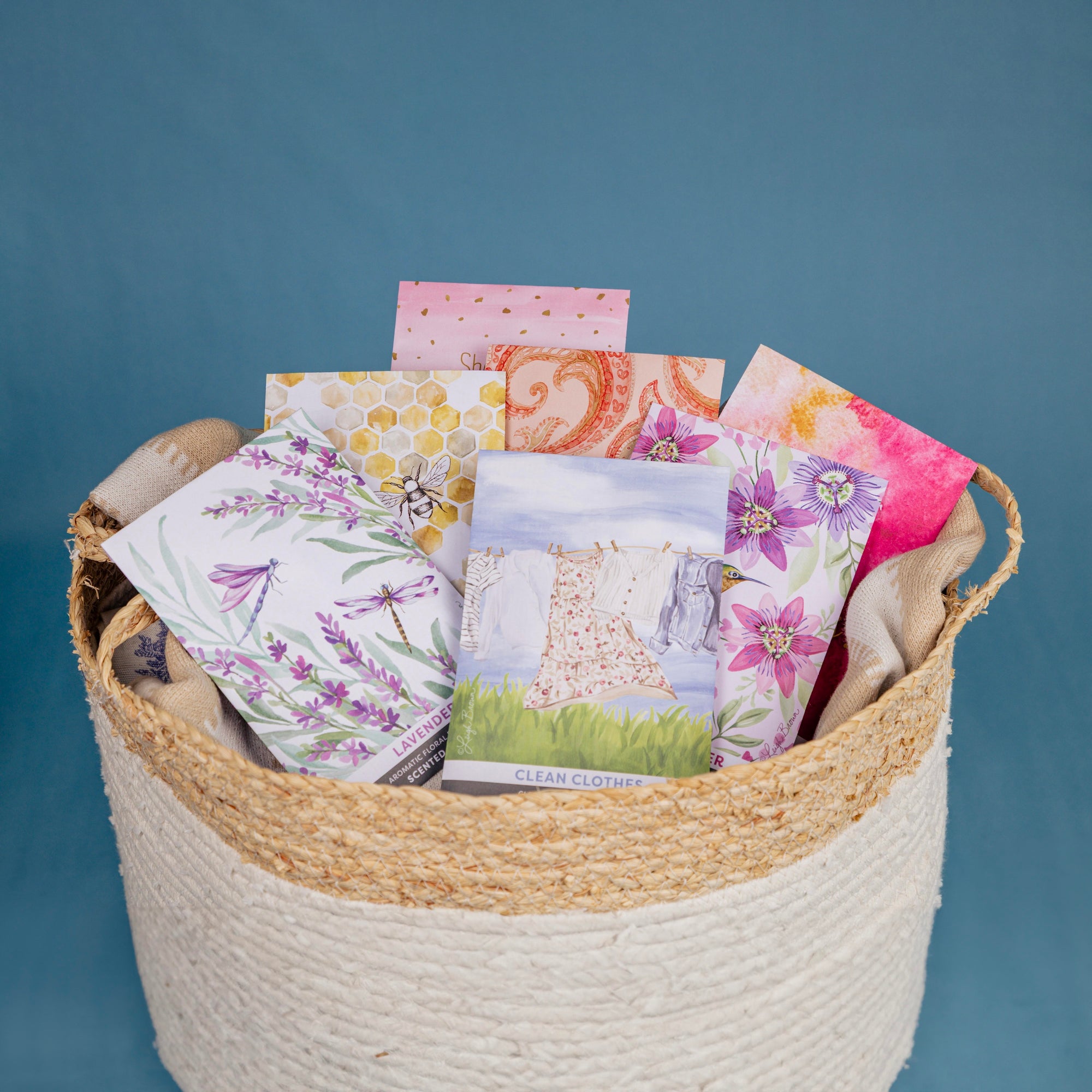 Assorted scented sachets from fresh scents in woven basket with dark blue background.