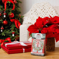 Load image into Gallery viewer, A festive living room with a decorated Christmas tree, two red-wrapped gifts, a poinsettia in a basket, and a Fresh Scents Red Door Wreath - Sachet 3pk on the wooden table for long-lasting holiday fragrance.
