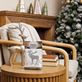 Load image into Gallery viewer, A festive scene featuring a glittery reindeer figurine and Fresh Scents Woodland Sachet 3pk on a round wooden table, beside a beige armchair, stacked books, and a decorated Christmas tree in the background.
