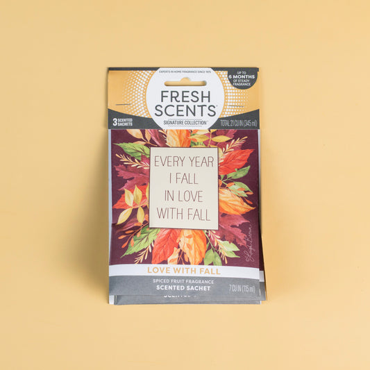 The Fresh Scents Love with Fall - Sachet 3pk features autumn leaves and "Every year I fall in love with fall" on the front, offering a perfect long-lasting flameless fragrance. Set against a plain beige background.
