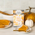 Load image into Gallery viewer, A Fresh Scents Autumn Leaves - Sachet 3pk box sits on a counter with autumn decorations, a white pumpkin, pumpkin pie, and long-lasting fragrant sachets, plus a plate with a slice of pie and a fork.
