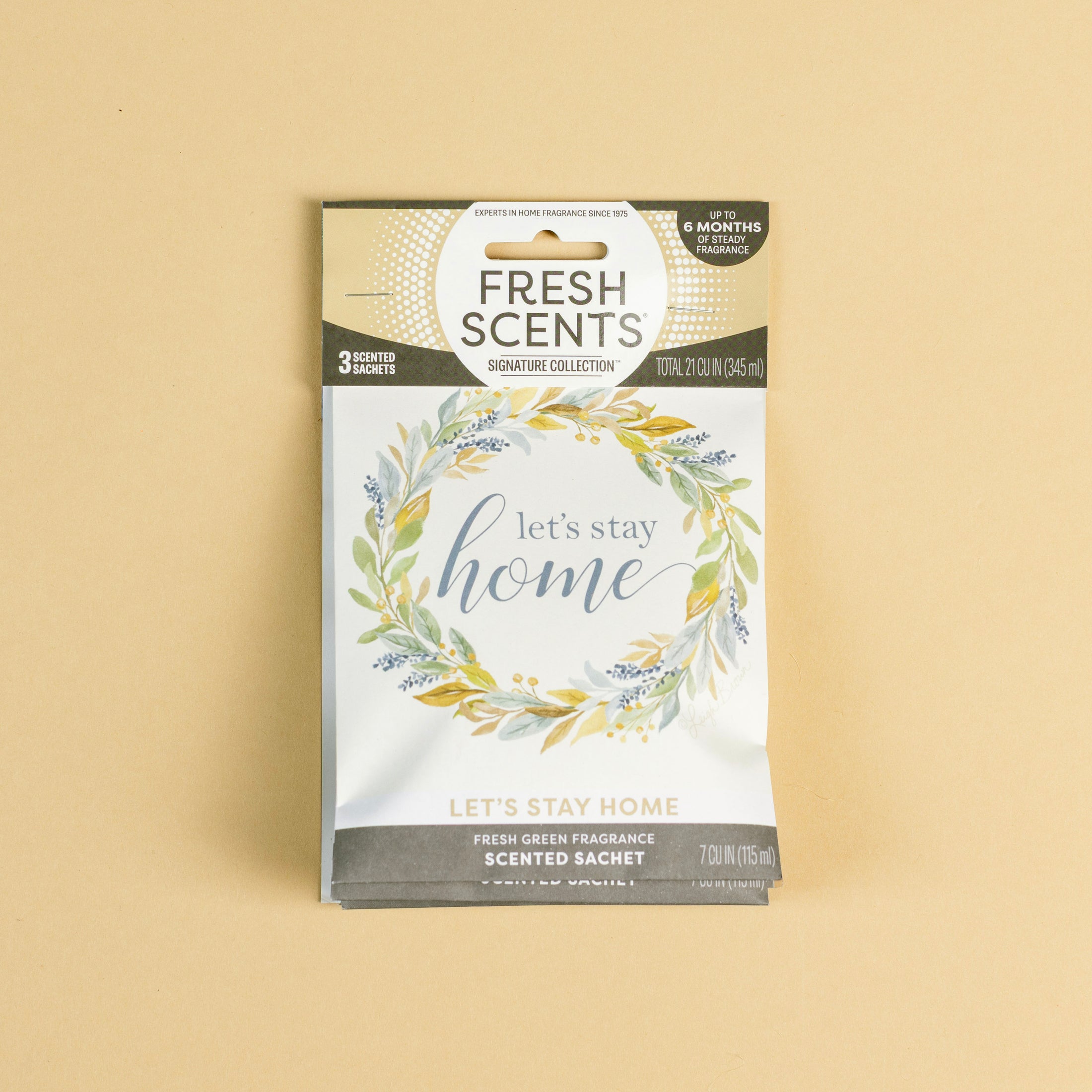 The Fresh Scents Lets Stay Home - Sachet 3pk features a floral wreath design with "let's stay home" on the front—an ideal flameless air freshener that offers long-lasting fragrance, shown here on a plain beige background.