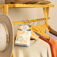 Load image into Gallery viewer, A wooden clothing rack holds several sweaters on hangers, a gray hat on the side, and a Fresh Scents Spiced Pumpkin - Sachet 3pk for long-lasting freshness among the clothes. Shoes are arranged on the top shelf.
