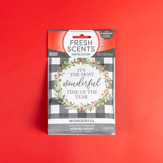 A Fresh Scents Wonderful - Sachet 3pk on a red background shows a wreath and "It's the most wonderful time of the year." This flameless air freshener features a warm, spicy, long-lasting scent.
