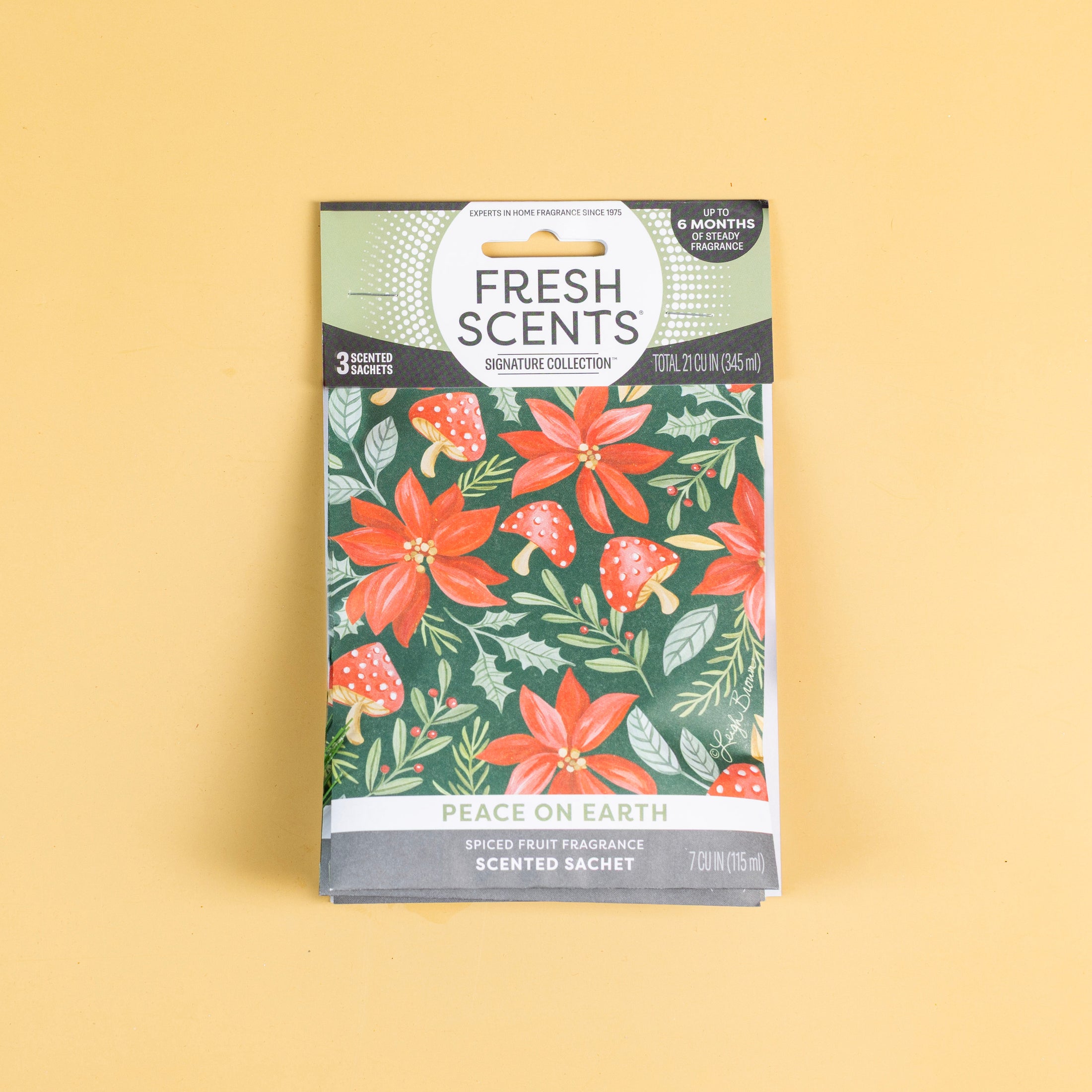 A 3-pack of sachets from Fresh Scents, labeled “Peace on Earth,” features a holiday floral and mushroom design on a yellow background. These sachets offer a spiced fruit fragrance, providing a long-lasting, flameless way to freshen your space.